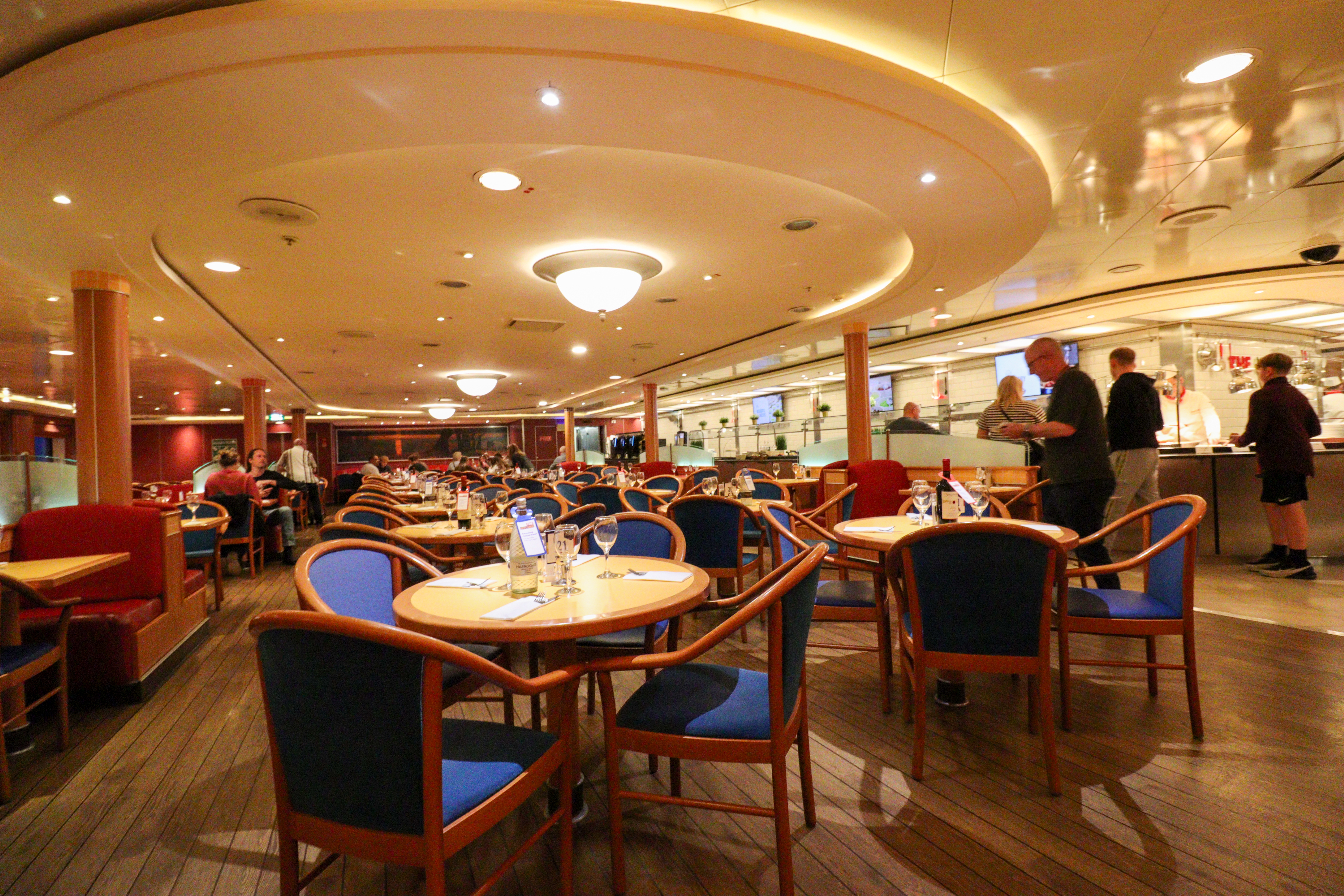 Clean, well lit restaurant with tables laid for dinner and a buffet area in the background.